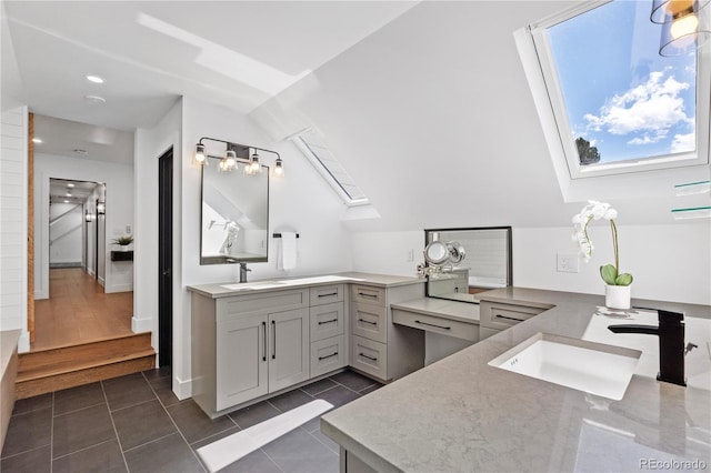 bathroom featuring wood-type flooring, vanity, and vaulted ceiling with skylight