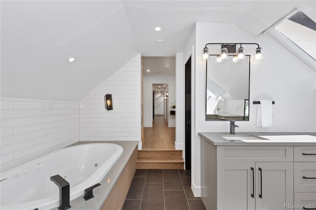 bathroom featuring tile patterned flooring, vanity, a relaxing tiled tub, and vaulted ceiling