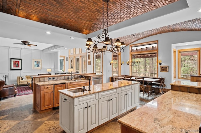 10231 Democrat Rd, Parker, CO 80134 - kitchen with an island with sink, a tray ceiling, open floor plan, a chandelier, and light stone counters