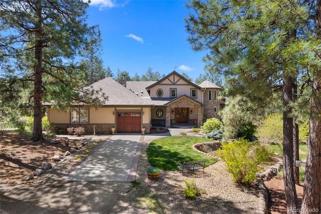 10231 Democrat Rd, Parker, CO 80134 - tudor house featuring stone siding, an attached garage, driveway, and stucco siding