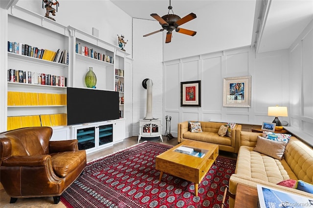 10231 Democrat Rd, Parker, CO 80134 - living room featuring a ceiling fan, a wood stove, a decorative wall, and a towering ceiling