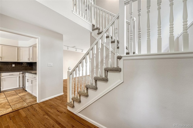 stairway featuring rail lighting and wood-type flooring