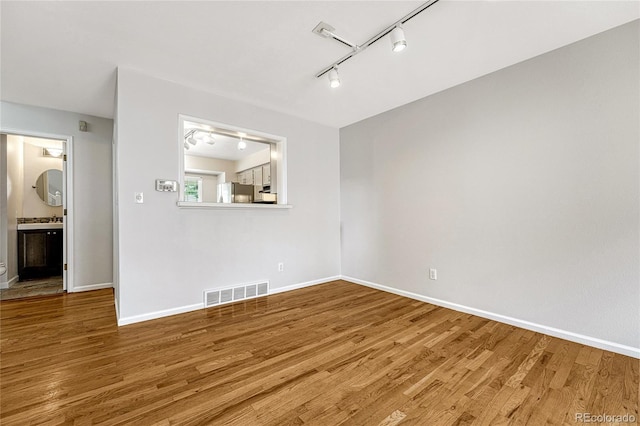 unfurnished living room featuring track lighting and wood-type flooring