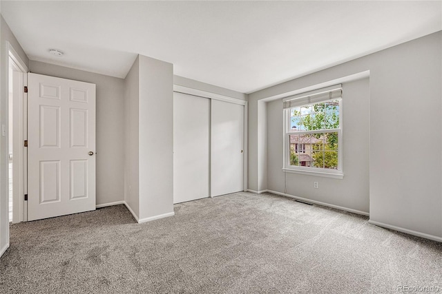 unfurnished bedroom with light carpet and a closet