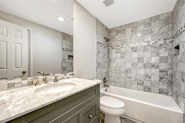 full bathroom with tiled shower / bath, vanity, and toilet