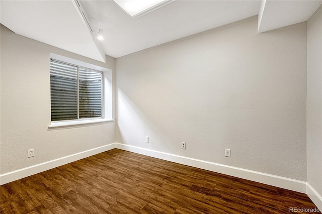 spare room featuring vaulted ceiling and dark hardwood / wood-style floors