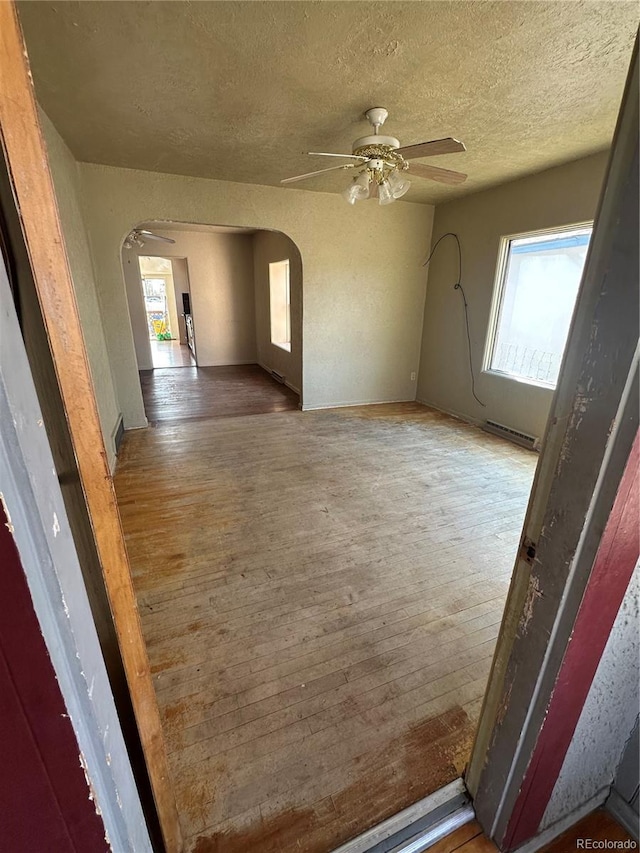 1114 La Due Ave, Alamosa, CO 81101 - unfurnished room featuring arched walkways, a wealth of natural light, ceiling fan, and hardwood / wood-style flooring