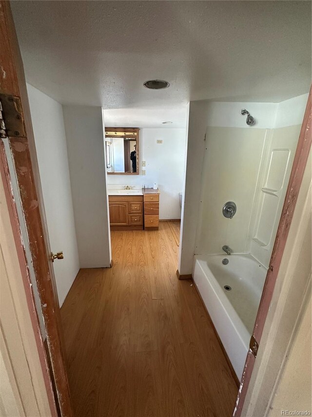 1114 La Due Ave, Alamosa, CO 81101 - bathroom featuring  shower combination, vanity, a textured ceiling, and wood finished floors