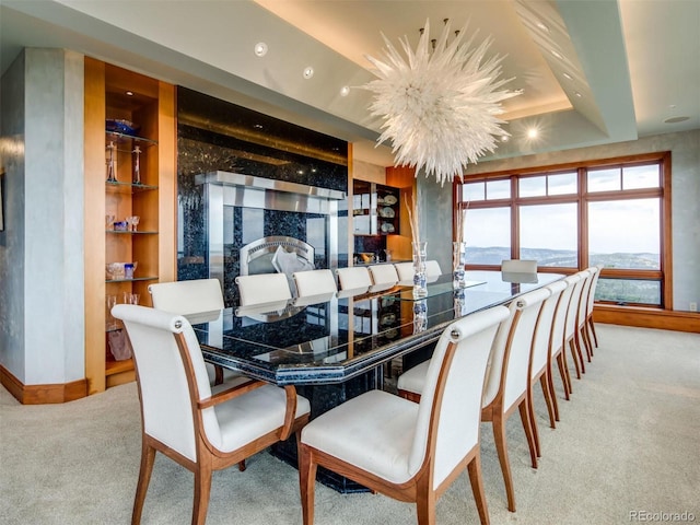 dining space with a notable chandelier, a raised ceiling, and light carpet