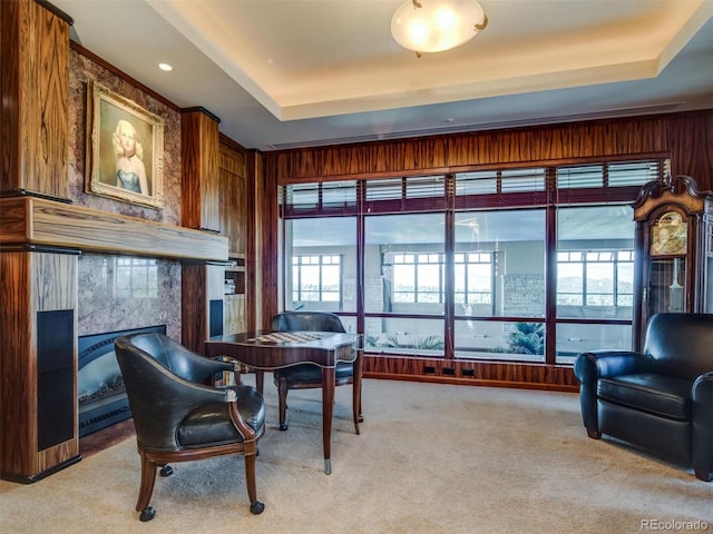 office space featuring a fireplace, a raised ceiling, and light carpet