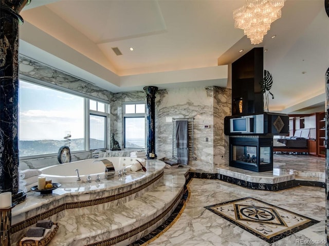 bathroom featuring a high end fireplace, a notable chandelier, and a washtub