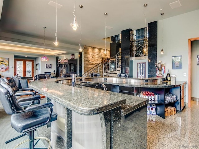 bar featuring stone countertops and hanging light fixtures