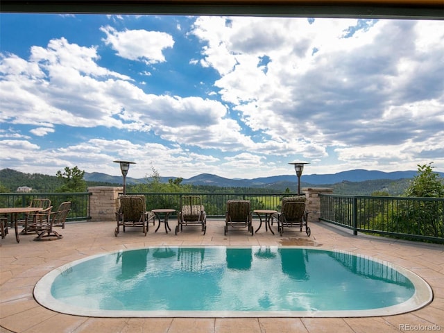 view of swimming pool with a patio and a mountain view