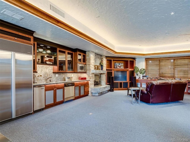 living room with a textured ceiling, a raised ceiling, carpet flooring, and a fireplace