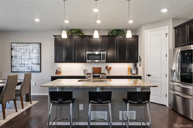 kitchen featuring dark wood finished floors, light stone counters, appliances with stainless steel finishes, and a sink