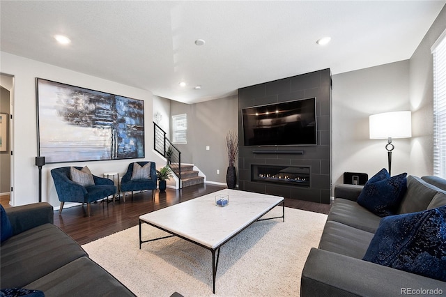 living room featuring wood finished floors, recessed lighting, a fireplace, baseboards, and stairs