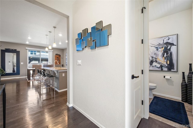 hall featuring recessed lighting, baseboards, and dark wood-style flooring