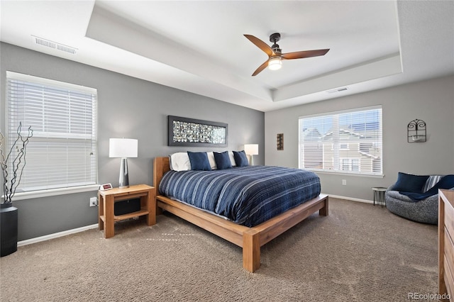 carpeted bedroom with visible vents, ceiling fan, a raised ceiling, and baseboards