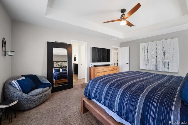 carpeted bedroom with a raised ceiling and ceiling fan