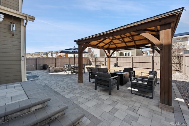 view of patio with outdoor dining area, a fenced backyard, an outdoor living space with a fire pit, a gazebo, and a residential view