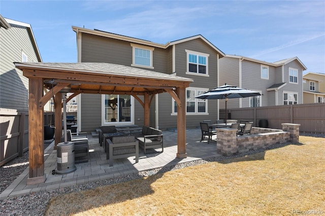 rear view of property featuring a gazebo, an outdoor living space, a patio, and a fenced backyard