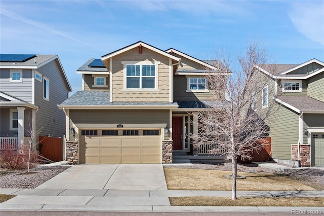 craftsman inspired home with stone siding, fence, concrete driveway, a garage, and solar panels