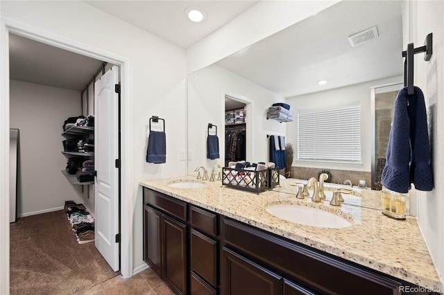 bathroom with a sink, visible vents, a spacious closet, and double vanity