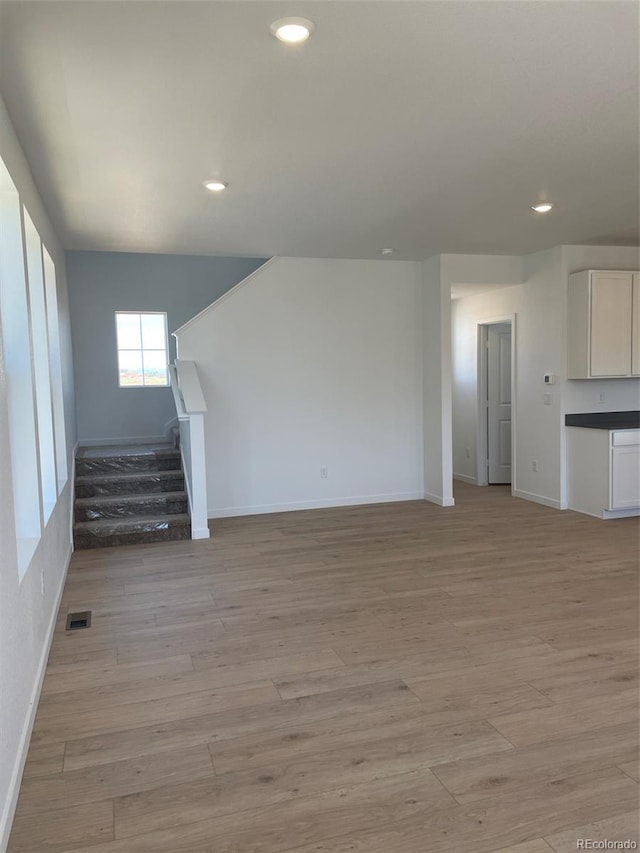 6657 E 149th Dr, Thornton, CO 80602 - unfurnished living room with stairs, light wood finished floors, baseboards, and recessed lighting