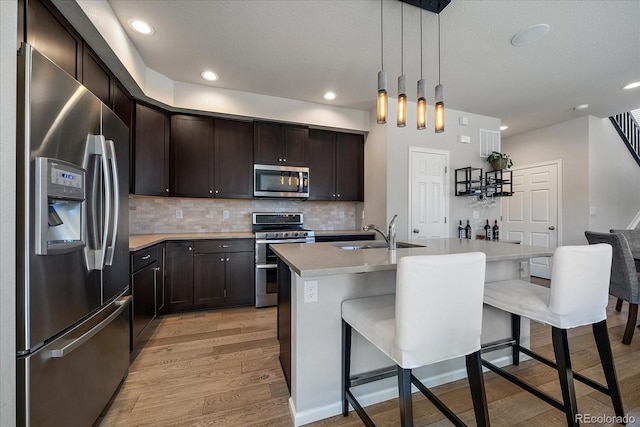 kitchen featuring a sink, a kitchen breakfast bar, appliances with stainless steel finishes, and light wood-style flooring