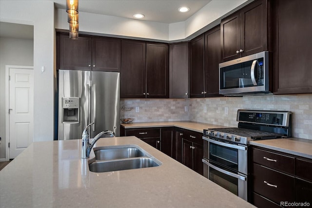 kitchen with decorative backsplash, dark brown cabinets, stainless steel appliances, and a sink