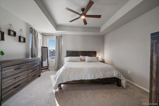 bedroom with ceiling fan, a raised ceiling, baseboards, and light carpet