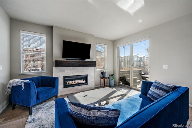 living area featuring a glass covered fireplace, baseboards, and wood finished floors