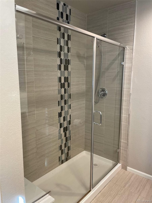 full bath with a shower stall and baseboards