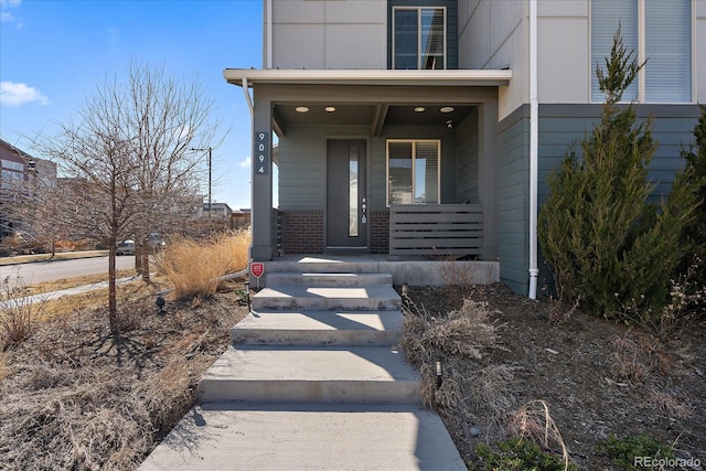 property entrance featuring brick siding and covered porch