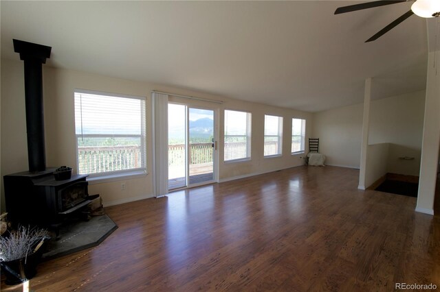 living room with ceiling fan, a wood stove, and hardwood / wood-style flooring