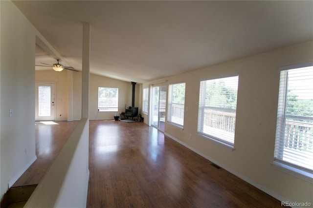 unfurnished living room with ceiling fan, a wood stove, wood-type flooring, and vaulted ceiling