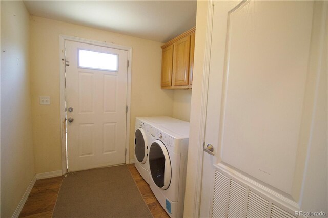 clothes washing area featuring independent washer and dryer, wood-type flooring, and cabinets