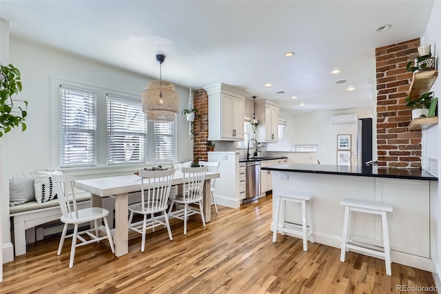 kitchen with decorative light fixtures, a kitchen breakfast bar, dishwasher, a wall unit AC, and white cabinets