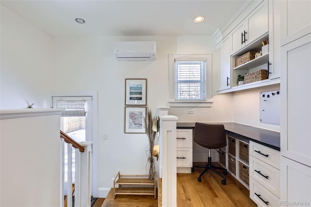 office space with recessed lighting, light wood-style floors, built in desk, and a wall mounted air conditioner