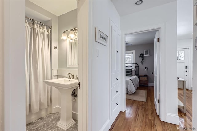 full bathroom with a shower with shower curtain, wood finished floors, baseboards, and a sink