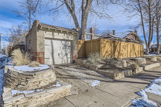 view of home's exterior with a tile roof, fence, an outdoor structure, a garage, and brick siding