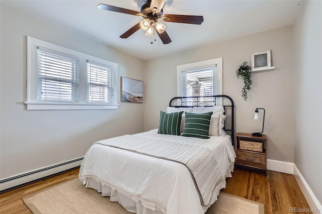 bedroom featuring a ceiling fan, wood finished floors, baseboards, and a baseboard radiator