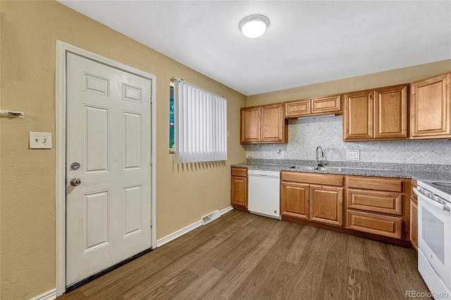 kitchen with backsplash, dark hardwood / wood-style floors, sink, and white appliances