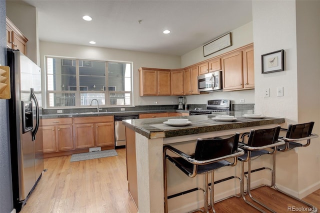 kitchen featuring appliances with stainless steel finishes, a kitchen breakfast bar, kitchen peninsula, and light hardwood / wood-style floors