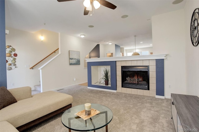 carpeted living room with a tile fireplace and ceiling fan