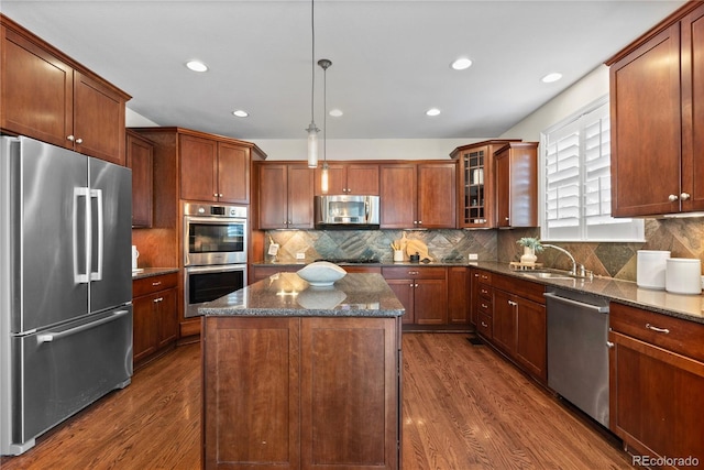 10840 Valleybrook Cir, Highlands Ranch, CO 80130 - kitchen with appliances with stainless steel finishes, dark wood-style floors, a kitchen island, dark stone countertops, and decorative backsplash