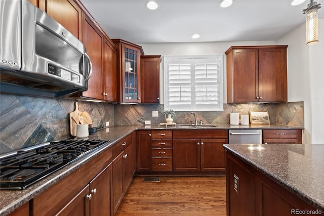 10840 Valleybrook Cir, Highlands Ranch, CO 80130 - kitchen featuring stainless steel appliances, dark wood finished floors, dark stone counters, glass insert cabinets, and tasteful backsplash