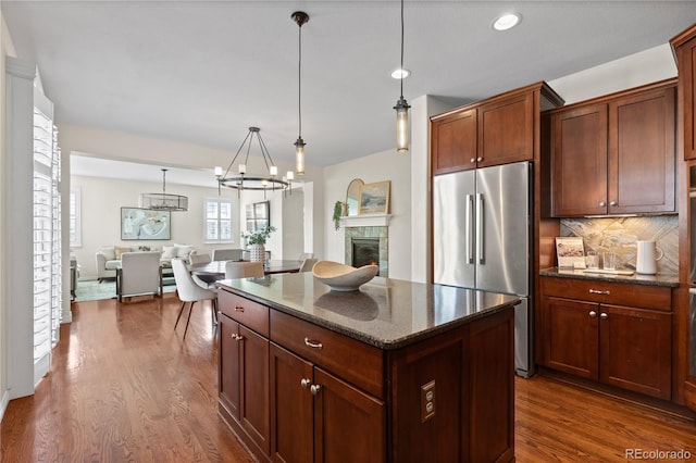 10840 Valleybrook Cir, Highlands Ranch, CO 80130 - kitchen featuring freestanding refrigerator, dark wood-style flooring, a kitchen island, a tile fireplace, and recessed lighting