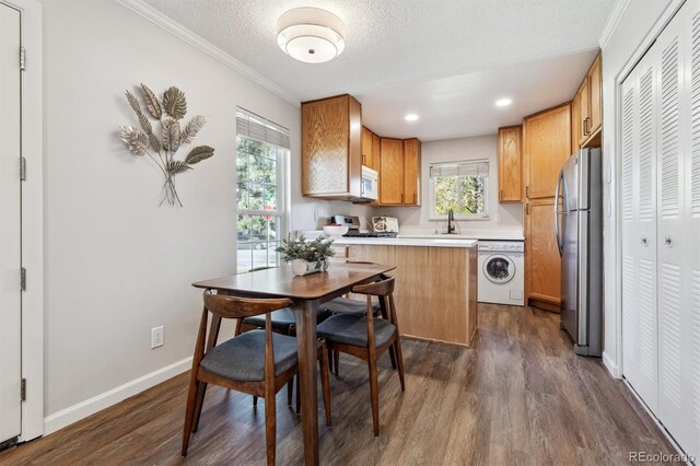 kitchen featuring washer / dryer, dark wood finished floors, a breakfast bar area, freestanding refrigerator, and light countertops