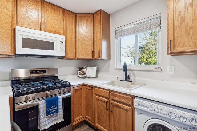 kitchen featuring stainless steel gas range oven, white microwave, a sink, light countertops, and washer / dryer